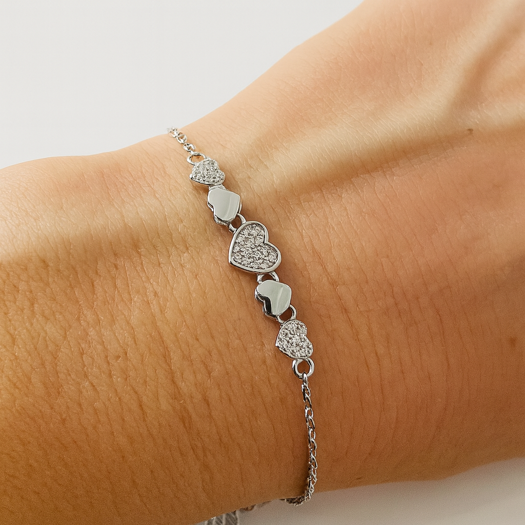 Brățară elegantă din argint 925 rodiat cu inimioare strălucitoare și lanț subțire, lungime ajustabilă 16+3 cm, fotografiată pe fundal alb lucios tip e-commerce, simbol al iubirii și rafinamentului feminin, pe mana

